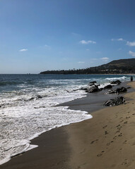 Beautiful Californian sandy beach with wake of Pacific Ocean on West Coast with volleyball fields,...