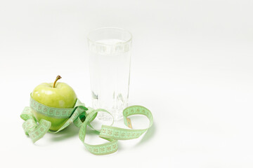 green apple, centimeter and glass of water on a white background