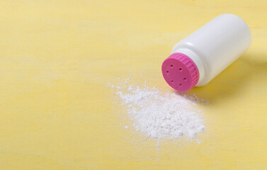 Closeup of baby powder on the yellow background.White bottle with pink cap of baby powder