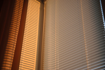 Sunset sun shines through the blinds. Golden hour.