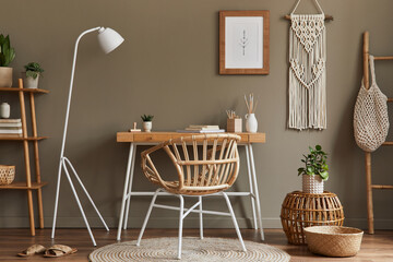 Modern composition at boho interior of home office room with wooden desk, stylish armchair, bamboo...