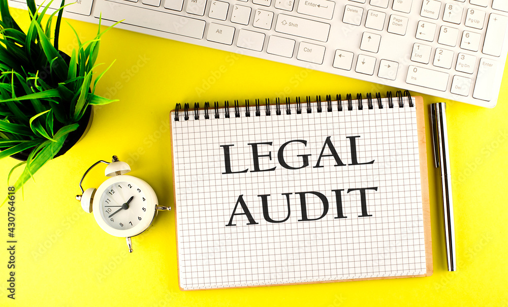 Poster legal audit text on notebook with keyboard , pen and alarm clock on the yellow background