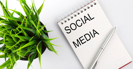 Keyword SOCIAL MEDIA - business concept text on a white notebook and pen, green flowers