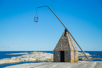 Replica of an old lighthouse. Serene Scandinavian summer landscape on south coast of Norway. Rocky sea shore, fjord. Clear blue sky.  Verdens Ende, Tjøme, Norway