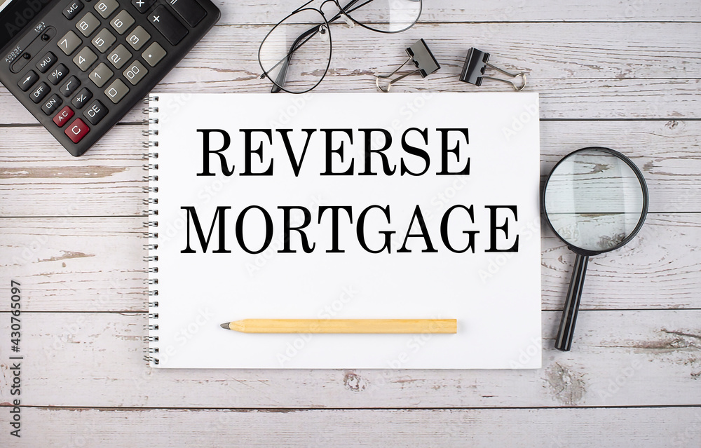 Poster blank notebook with text reverse mortgage on white background with calculator and office tools.