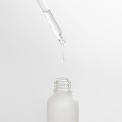 Pipette drips clear serum into the bottle. Dropper and drop of natural serum.