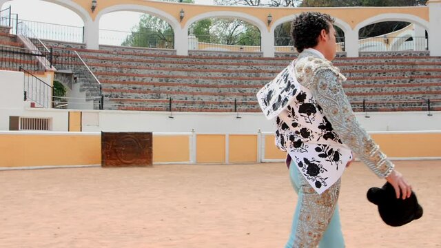 Bullfighter in blue suit of lights slowly walking in the bullring