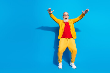Full size photo of shocked amazed surprised grandfather dancing wear yellow tracksuit isolated on blue color background