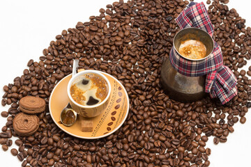 Cup of coffee with froth, spoon with froth on saucer. Turk with brewed coffee. Chocolate chip cookies. Grains of coffee on table