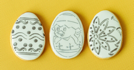 Easter glazed cookies in the form of eggs on a yellow background that can be painted with a brush and food colors