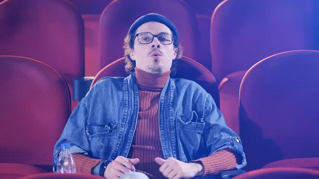 A man is getting tense while watching a film at the cinema