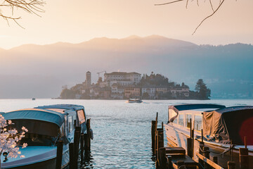 View of the San Giulio island on Lake Orta with tourist boat sailing on the lake at sunset