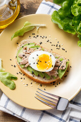 Avocado, canned tuna and boiled egg toast on wooden table background. Healthy food, avocado open sandwich for breakfast or lunch. Flat lay, top view