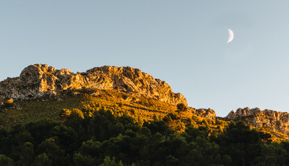 Sunset on mountain peak with waning moon