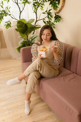 Obraz premium Pretty woman are eating asian fast food from box in bed-room. Delicious Wok noodles. Eat at home. Vertical photo.