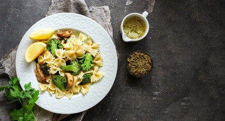 Farfalle with broccoli and chicken and basil. Italian food. Top view. Dark background. Copy space.