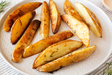 Homemade Rosemary Potato Wedges on a plate, side view. Close-up.