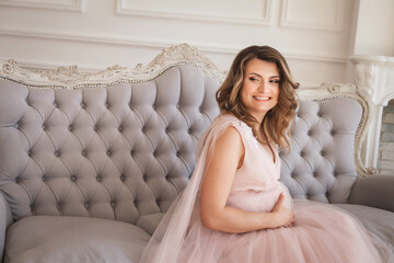 Young pregnant woman sitting on sofa and smiling