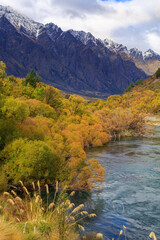 Autumn landscape near Queenstown, New Zealand. The Kawarau River, surrounded by willows, and the Remarkables mountain range