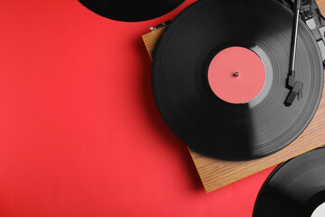Modern player and vinyl records on red background, flat lay. Space for text