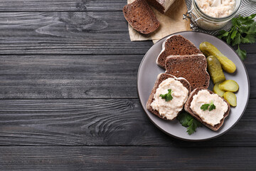 Delicious sandwiches with lard spread on black wooden table, flat lay. Space for text