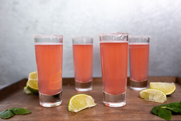 four pink cocktails with limes on a wooden stand