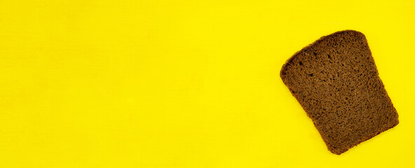 A slice of rye bread isolated on a yellow background close up with a blank space for your text