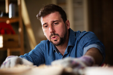 Carpenter working on wood craft at workshop. Young man working in workshop.