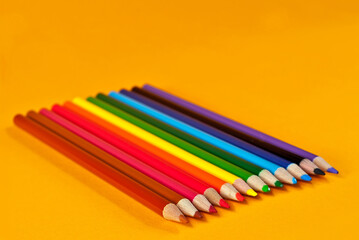 Multicolored pencils on an orange background. Copy space and free space for text on yellow background.