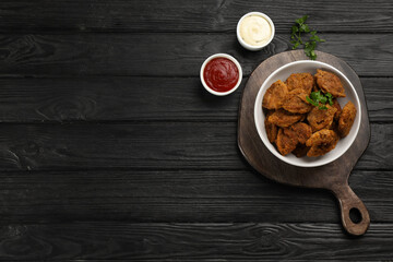 Cooked soy meat in bowl on black wooden table, flat lay. Space for text