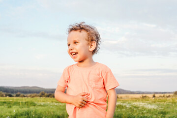 Naklejka na ściany i meble Little boy in a meadow, sunset light.