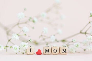 Happy Mother's Day. Text i love mom on pink background with blur gypsophila flowers . Greeting card.