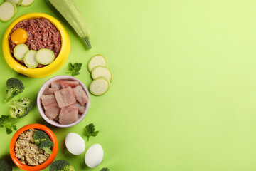 Pet food and natural ingredients on green background, flat lay. Space for text