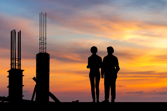Silhouette of Engineer and worker with clipping path on building site, the construction site at sunset in the evening time