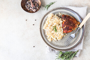 Baked chicken breast with rice on a plate served with roasted vegetables. Top view.