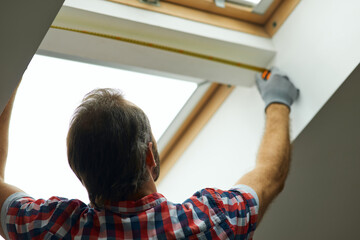 Obraz premium Close up shot of handyman using measure tape while measuring a window in a new dry wall attic