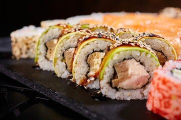 Sliced sushi rolls with crab meat and avocado drizzled with sauce and sprinkled with sesame seeds.