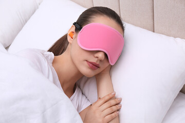 Young woman with foam ear plugs and mask sleeping in bed