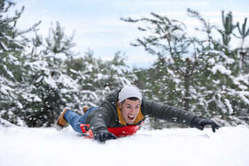Fototapeta na wymiar Happy man sledding outdoors on winter day. Christmas vacation