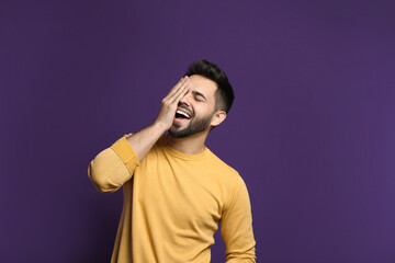Young man laughing on purple background. Funny joke