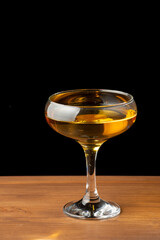 Top view of whiskey cocktail glass on wooden table, black background, vertical, with copy space