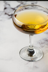 Aerial view of cocktail glass on white marble table, selective focus, vertical, with copy space