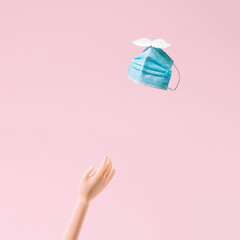 The end of the epidemic. Removing the mask. Freedom. A flying mask. The end of the corona. Pink wallpaper. Minimal composition.