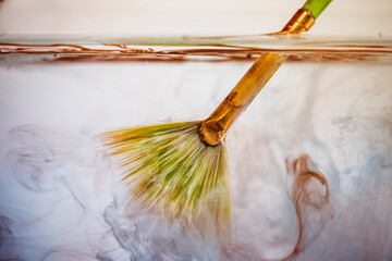 Brush with paints in clear water. paints dissolve on a white background