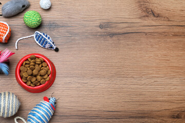 Different pet toys and feeding bowl on wooden background, flat lay. Space for text