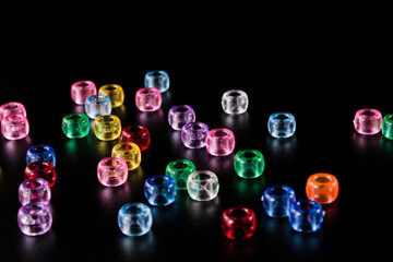 Scattered illuminated transparent colourful beads, isolated on black background