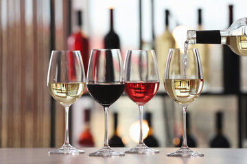 Pouring white wine from bottle into glass on table indoors