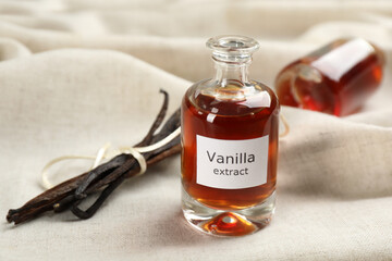 Vanilla extract and dry pods on white cloth
