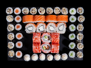 Top view of sushi rolls philadelphia and california placed in a square of small maki rolls.