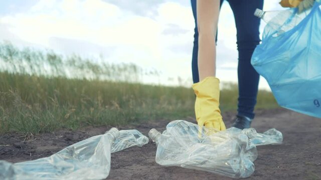 volunteer collects plastic trash in the park. recycle plastic bottle cleanup ecology concept blurred background. clean girl volunteer gloves collects plastic bottles and glasses in a trash bag